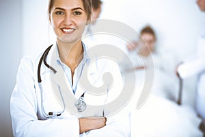 Female doctor smiling on the background with patient in the bed and two doctors