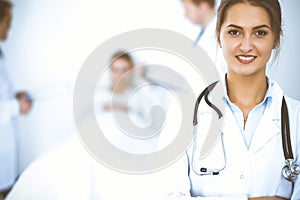 Female doctor smiling on the background with patient in the bed and two doctors