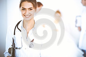 Female doctor smiling on the background with patient in the bed and two doctors