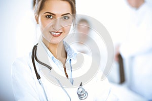 Female doctor smiling on the background with patient in the bed and two doctors