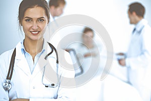 Female doctor smiling on the background with patient in the bed and two doctors