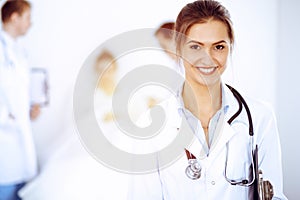 Female doctor smiling on the background with patient in the bed and two doctors