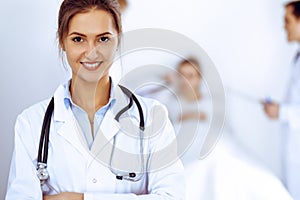 Female doctor smiling on the background with patient in the bed and two doctors