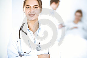 Female doctor smiling on the background with patient in the bed and two doctors