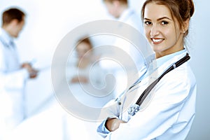 Female doctor smiling on the background with patient in the bed and two doctors