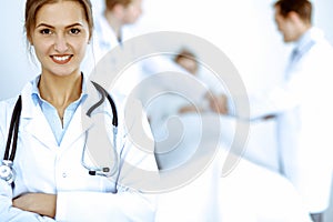 Female doctor smiling on the background with patient in the bed and two doctors