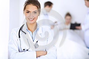 Female doctor smiling on the background with patient in the bed and two doctors