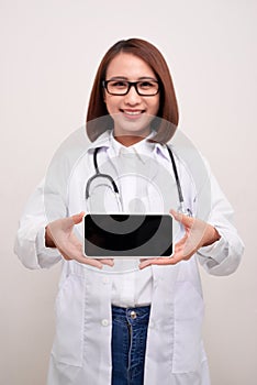 Female doctor smiling and showing a blank smart phone screen isolated on a white background