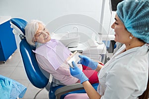 Female doctor smiling to patient while holding shade guide