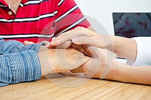 Female doctor soothes a female patient in hospital consulting room while holding the patients hands. Healthcare and medical