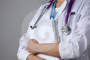 Female doctor standing with medical stethoscope holding a folder , on gray background