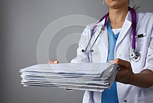 Female doctor standing with medical stethoscope holding a folder , on gray background