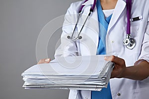 Female doctor standing with medical stethoscope holding a folder , on gray background