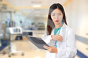 Female doctor standing at work in hospital with lab coat and stethoscope holding medical folder in hand