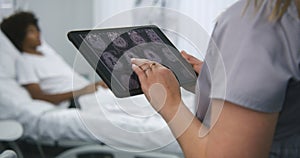 Female doctor stands in hospital room, uses digital tablet computer