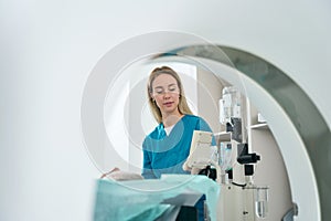 Female doctor stands near the patient in the tomography room