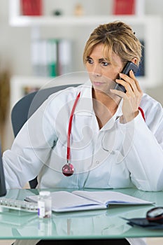 Female doctor with stethoscope around neck on phone