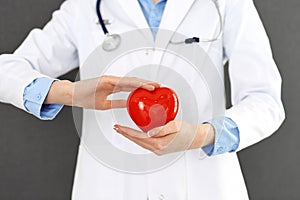 Female doctor with stethoscope holding heart in her arms. Healthcare and cardiology concept  in medicine