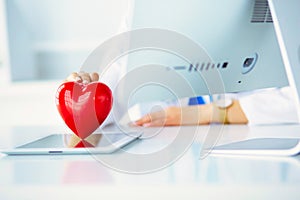 Female doctor with stethoscope holding heart, on light background