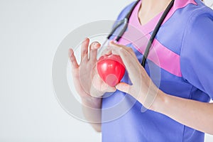 Female doctor with stethoscope holding red heart, isolated on white background, heart healthy care concept with copy space.