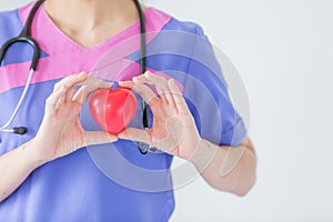 Female doctor with stethoscope holding red heart, isolated on white background, heart healthy care concept with copy space.