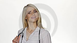 Female doctor with stethoscope smiling to camera. White