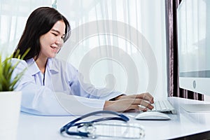 Female doctor with stethoscope typing on keyboard desktop computer
