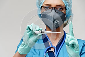 Female doctor with stethoscope wearing protective mask and latex gloves over light grey background holding thermometer