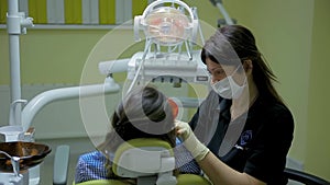 Female doctor stomatologist at work treats and whitens teeth to young woman patient in medical dental clinic