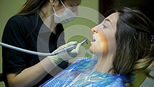 Female doctor stomatologist at work treats and whitens teeth to young woman patient in medical dental clinic