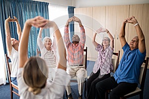 Female doctor stretching with seniors sitting on chairs