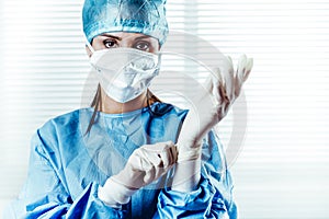 Female doctor Surgeon putting on surgical gloves photo