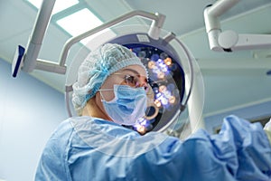 Female Doctor in Surgery Operating Hospital Room. Surgeon medic in protective work wear gloves, mask and cap