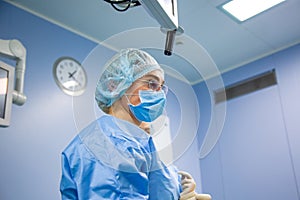 Female Doctor in Surgery Operating Hospital Room. Surgeon medic in protective work wear gloves, mask and cap