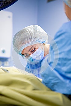 Female Doctor in Surgery Operating Hospital Room. Surgeon medic in protective work wear gloves, mask and cap