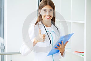 Female Doctor In Surgery Reading Patient Notes