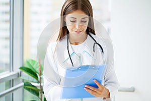 Female Doctor In Surgery Reading Patient Notes