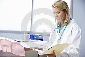 Female Doctor In Surgery Reading Patient Notes