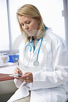 Female Doctor In Surgery Writing Out Prescription