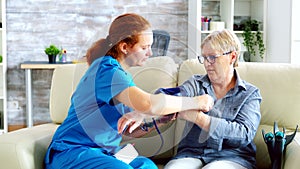 Female doctor taking blood pressure of senior woman