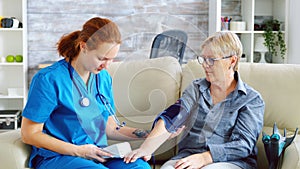 Female doctor taking blood pressure of senior woman