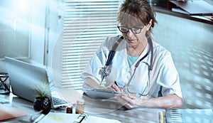 Female doctor taking notes on clipboard; light effect