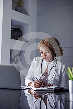 Female doctor taking notes while having video call with patient
