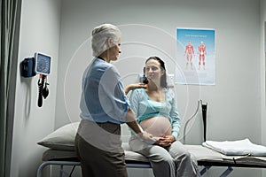 Female doctor talking with pregnant woman in examination room