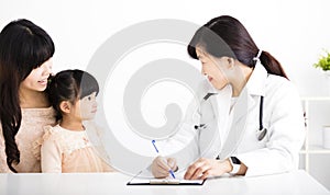 Female doctor talking to child and mother