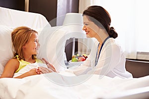 Female Doctor Talking To Child Patient In Hospital Bed