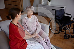 Female doctor talking to her patient during home visit