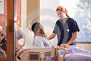 Female Doctor Talking To Male Patient In Hospital Bed