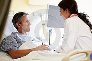 Female Doctor Talking To Male Patient In Hospital Room