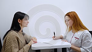 Female doctor talking to patient and filling in medical form